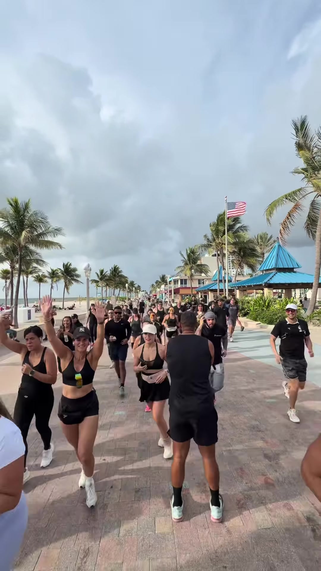Diamond Running Club crowd with hands raised on the beach boardwalk
